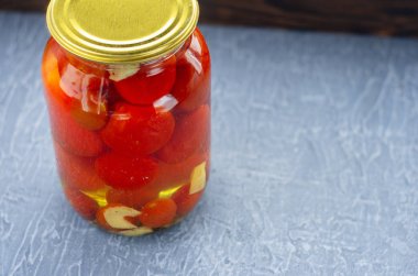 Hafif ahşap arka plan üzerinde kırmızı peçeteye bir kavanoza tuzlu kırmızı domates. Fermente sebze.