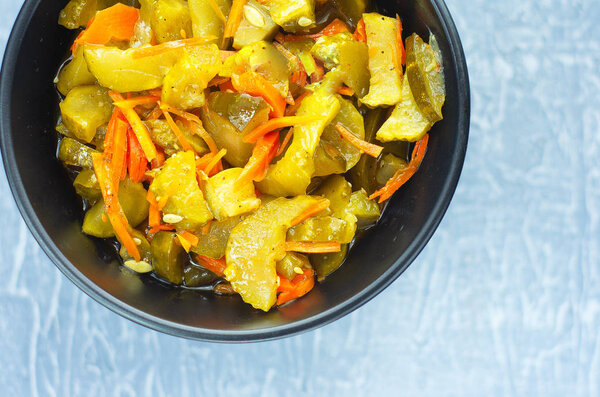 pickled fermented cucumbers and carrots in a dark salad bowl. View from above.