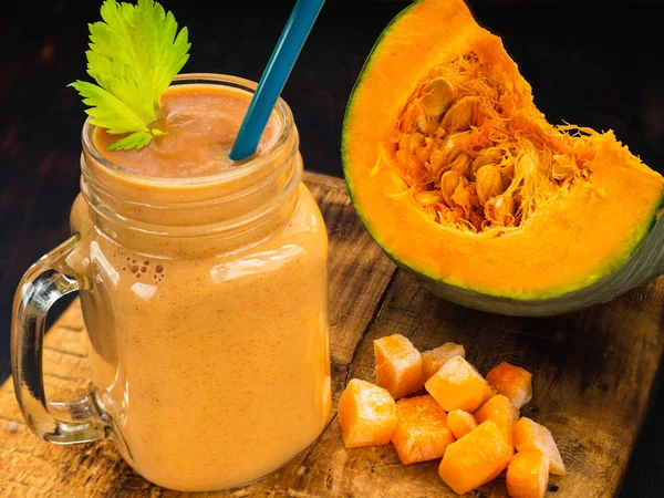 Batidos de calabaza con hojas de apio con un trozo o trozos de calabaza y una paja — Foto de Stock