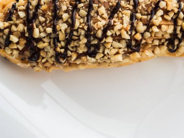 Çikolata ekler beyaz bir plaka üzerinde fındık serpilir