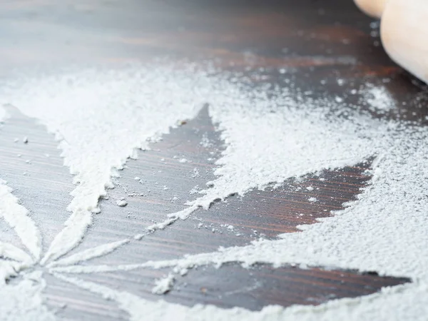 Cannabis kochen. Spuren von Cannabisblättern auf weißem Mehl. auf einem Holztisch — Stockfoto