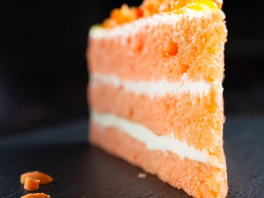 Sünger havuçlu kek koyu doğal bir levhada. Keklerin iç katmanları görünür..