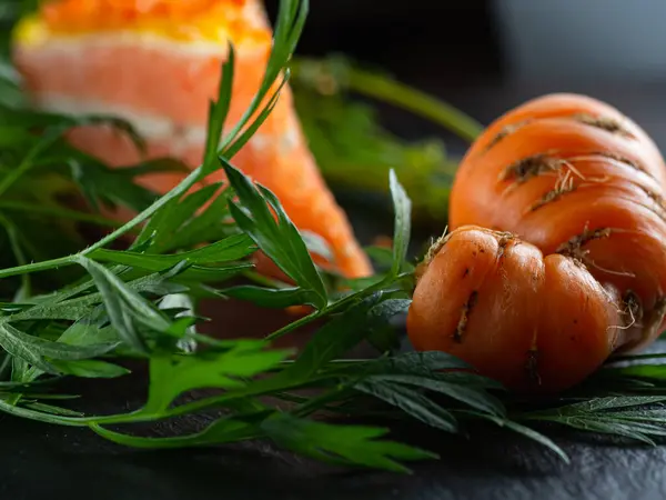 Потворна свіжа морква з зеленим листям. На задньому плані морквяний пиріг . — стокове фото