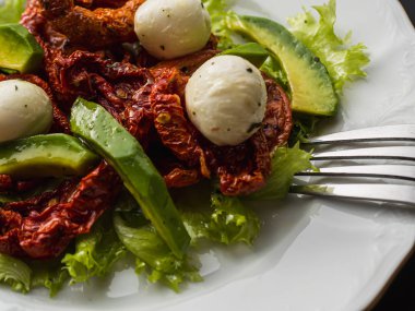 Kurutulmuş domateslerden, pe-tsai, avokado ve mozzarella peynirinden yapılmış salata. yakın plan.