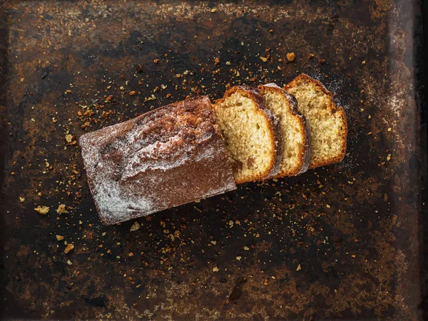 Rectangular loaf cut into pieces with a white sprinkle is on a rusty protvin.