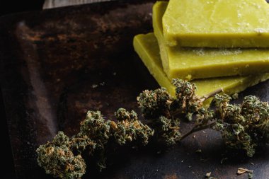 Eski paslı metal damlayan tavada rustik kenevir yağı ve tıbbi marihuana tomurcuğu. Eski ahşap arka plan. yatay oryantasyon. yakın plan.