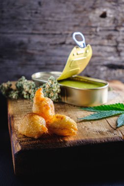 Tıbbi kenevir yağından, şekerden, undan, yumurtadan toplar. Marihuana tomurcukları. Tıbbi kenevir yağı açık bir teneke kutuda. Kenevir yaprakları. Eski ahşap bir arka planda. düşey yönelim.