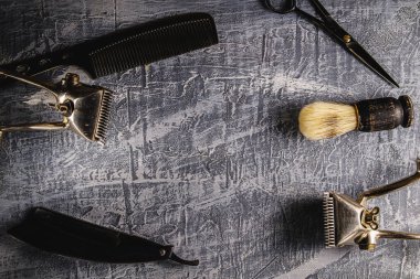 Boyalı bir beton yüzeyde eski kuaför aletleri vardır. İki klasik el yapımı saç makası, kuaför makası, tarak, tıraş bıçağı, tıraş fırçası. yatay oryantasyon. Üst Düz Görünüm
