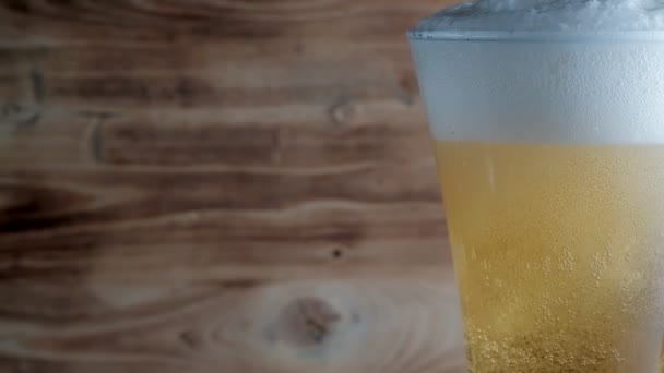 La cerveza fría se vierte en un vaso con una tapa blanca de Burbujas y Espuma. Material de archivo — Vídeos de Stock