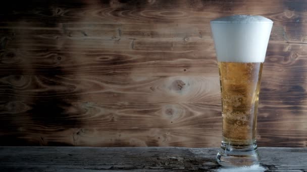 Cerveja gelada em vidro com uma tampa branca de espuma e bolhas. Imagens de stock — Vídeo de Stock