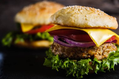 İki taze nefis ev yapımı sebzeli burger, sade ahşap arka planda doğal bir tahta üzerine uzanır. Marul, peynir, soğan ve domatesli lezzetli hamburger. Karabuğday ve mercimek pirzolası. yatay orinasyon
