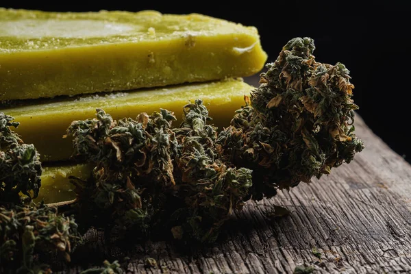 Eski paslı metal damlayan tavada rustik kenevir yağı ve tıbbi marihuana tomurcuğu. Eski ahşap arka plan. yatay oryantasyon. yakın plan.