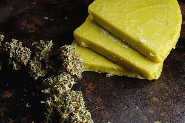 Eski paslı metal damlayan tavada rustik kenevir yağı ve tıbbi marihuana tomurcuğu. Eski ahşap arka plan. yatay oryantasyon. yakın plan.