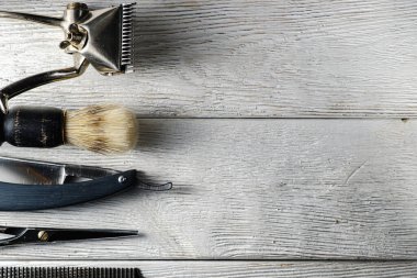 Eski el kuaförlüğü aletleri. El makası, kuaför makası, ustura, tıraş köpüğü için fırça. Beyaz yıpranmış ahşap arka planda. En üstteki düz yerde. yatay yönelimli. Boşluğu kopyala