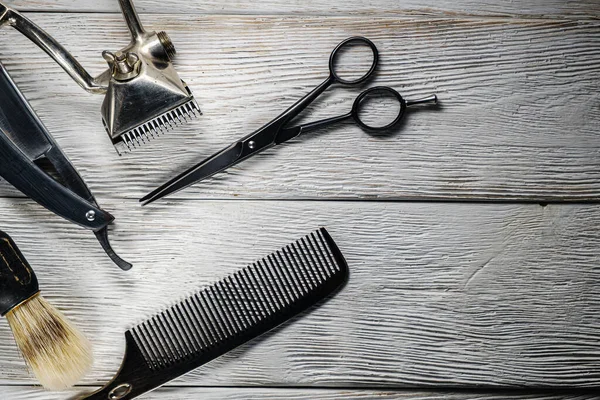 old hand hairdressing tools. Manual clipper, hairdressing scissors, straight razor, brush for shaving foam. on white weathered wood background. top view flat lay. horizontal orientetion