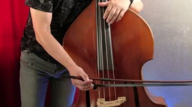Erkekler yayla bas çalıyor. Kapat. Erkek müzisyen yay tekniği uyguluyor. Klasik konserde kontrabass ritim. Akustik bas enstrümanı