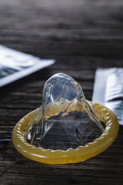 Dünya cinsel cehennem günü. Paketlenmemiş prezervatif eski ahşap bir arka planda paketlenmiş konilerin yanında duruyor. dramatik kare. kopyalama alanı. düşey yönelim.