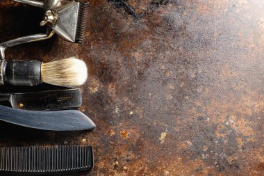 Paslı bir yüzeyde eski kuaför aletleri vardır. Manüel makas, tarak, jilet, tıraş fırçası. Kırsal kesim. yatay oryantasyon. Üst manzara düz ley. Boşluğu kopyala.