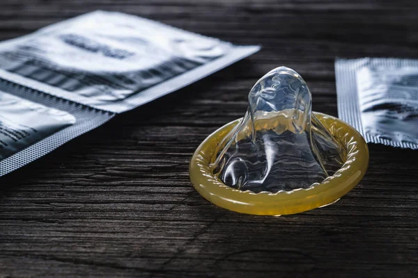 Dünya cinsel cehennem günü. Paketlenmemiş prezervatif eski ahşap bir arka planda paketlenmiş konilerin yanında duruyor. dramatik kare. kopyalama alanı. yatay yönelim.