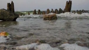 Dalgalar denizin yakınındaki harabe bir iskeleye çarpar. Gündoğumu Günbatımı. Hiç kimse. Genel plan.
