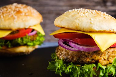 İki taze nefis ev yapımı sebzeli burger, sade ahşap arka planda doğal bir tahta üzerine uzanır. Marul, peynir, soğan ve domatesli lezzetli hamburger. Karabuğday ve mercimek pirzolası. yatay orinasyon