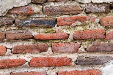 Beton kaplı eski tuğla duvar, hava yıpranmış beton tabaka uzakta altta yatan tuğla ortaya ufalanmış vardır. Decrepit durumu.