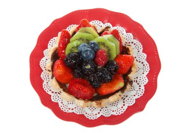 Çilek, kivi, yaban mersini, boysenberries beyaz arka plan üzerinde izole kırmızı plaka üzerinde beyaz doily ile Taze yaz meyve tart. Üstte görüntü.