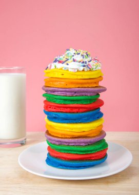 Parlak renkli krep yığını krem şanti ve şeker pembe arka plan ve süt cam ile serpilir ile tepesinde. Dikey sunum, Ulusal Uluslararası Pancake gün için Peri krep.