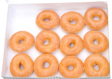 Beyaz bir kutu izole düz sırlı çörekler üst görünüm düz yatıyordu. Bir düzine eksi bir çörek. Orijinal sırlı donut tarih boyunca insanların favori kalmıştır.
