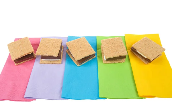 top view of many s\'mores lined up in a row on colorful napkins, ready for campfire party. Popular treat for Girl Scouts.