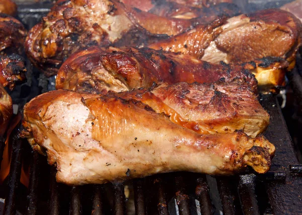 Turkey legs grilling on a BBQ grill. Giant turkey legs are a very popular food for street fair vendors.