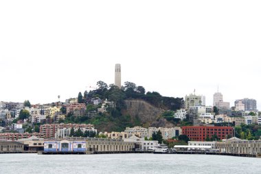 San Francisco 'daki Coit Kulesi, körfezden izleniyor. Coit Kulesi, San Francisco, Kaliforniya 'daki Telegraph Hill mahallesinde şehir ve körfez üzerinde panoramik görüntüler sunan 210 feet yüksekliğinde bir kuledir.. 