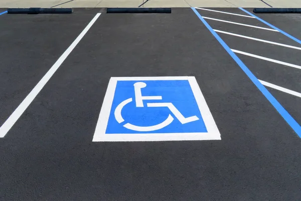 Freshly resurfaced and repainted handicap parking space in a parking lot. The number of handicap spaces increases with the size of the lot, requiring roughly one handicapped spot per 25 spaces.