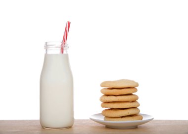 Küçük cam şişe taze süt ve şeker kamışı desenli çizgili kamış tabakta ev yapımı şeker kurabiyelerinin yanında..