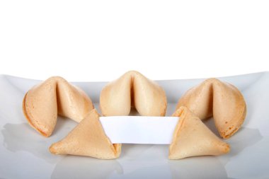 Talih kurabiyesi, mesajınız için boş kağıtla sergilenirken kırılmış. Arkasında el değmemiş kurabiyelerle porselen bir tabağa uzanmış, beyaz arka planda soyutlanmış..