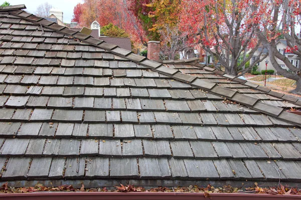 Wood shingle roof on house, rain gutters clogged with leaves, sticks and debris from trees.  Increased risk of rusting, increased need for maintenance and is a potential fire hazard.