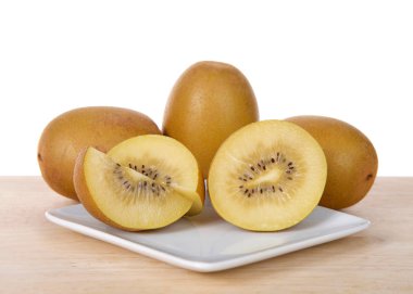 Sungold kivi ikiye bölünmüş ve tüm meyveler ahşap masada beyaz tabakta. Yeşil Kiwifruit 'in aksine, yeni Sungold Kiwifruit' in pürüzsüz bir teni vardır ve tipik Kivi meyvelerinden daha az asitlidir..