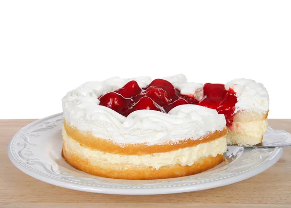 Strawberry short cake with cream filling on white plate, whipped cream and strawberries on top. Slice being pulled out of cake. On wood table isolated white background.