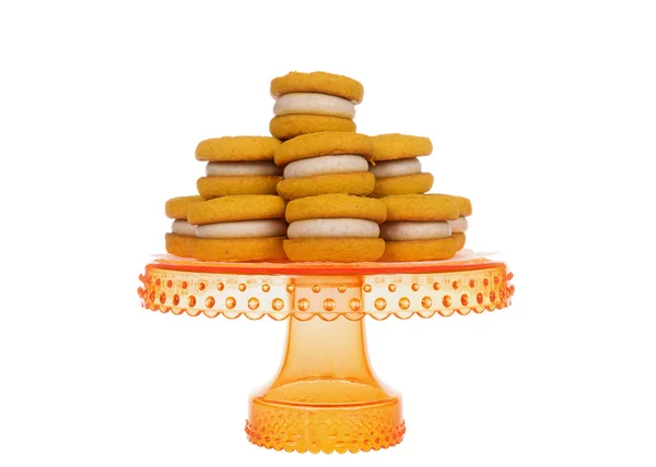 Naturally  flavored Pumpkin Spice cookies with cinnamon cream cheese filling on an orange pedestal isolated on white background.