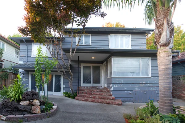 Kırık ahşap kaplamalı ve astar boyaya hazırlanan kırık ahşap kaplamalı cam kapaklı ve pencereli gri evin arka görüntüsü.