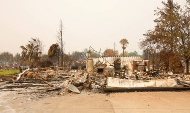 Ev yanıp kül oldu, garaj kapısı Redding, Ca 'daki yakın zamanda çıkan yangından sonra bir yığın haline geldi. Ateş kilometrelerce uzakta yanmaya devam ederken duman ve kül havada..