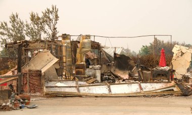Ev yanıp kül oldu, garaj kapısı Redding, Ca 'daki yakın zamanda çıkan yangından sonra bir yığın haline geldi. Ateş kilometrelerce uzakta yanmaya devam ederken duman ve kül havada..