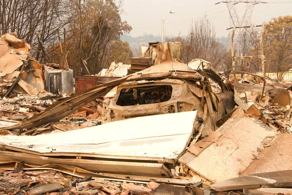 home burned to the ground, garage door buckled and laying in a heap after the recent wild fire fire storm in Redding, CA. Smoke and ash in the air as the fire continues to burn several miles away.