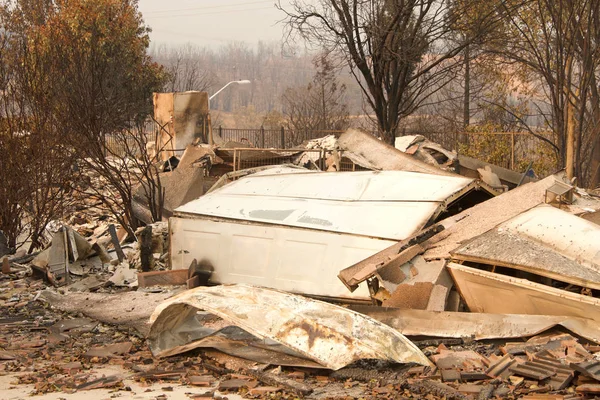 Ev yanıp kül oldu, garaj kapısı Redding, Ca 'daki yakın zamanda çıkan yangından sonra bir yığın haline geldi. Ateş kilometrelerce uzakta yanmaya devam ederken duman ve kül havada..