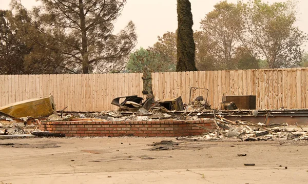 Ev yanıp kül olmuş, çitlere dokunulmamış. Redding, California 'daki son yangın fırtınasında. Ateş kilometrelerce uzakta yanmaya devam ederken duman ve kül havada..