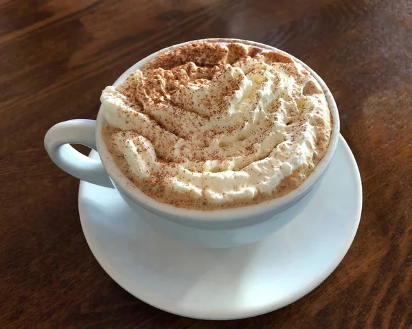 Tarçınlı mocha kahveyle dolu bir fincan porselen kahve. Üzerine krema serpilmiş tarçın serpiştirilmiş, yukarıdan izleniyor.