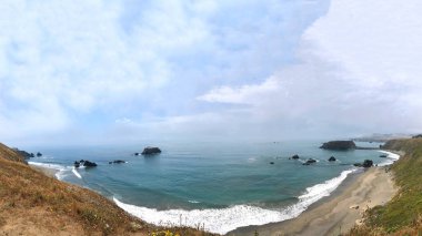 Kuzey Kaliforniya Pasifik Okyanusu Sahil Manzarası Keçi Sahili Eyalet Parkı sağda, deniz tabakası ufukta ve tepelerde geziniyor sağda izleyiciler.