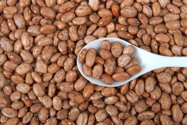 Beyaz kaşıkla fasulye yığınının içine dalan fasulye tanelerinin üzerinden düz bir manzara..