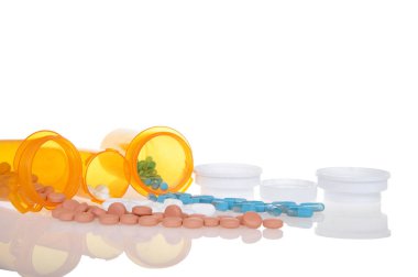 Haplar, turuncu ilaç şişelerinden izole edilmiş beyaz bir arka plana dökülüyor. Birden fazla reçeteyi takip etmek çok zor. Sağlık ve sağlık, bağımlılık kavramı