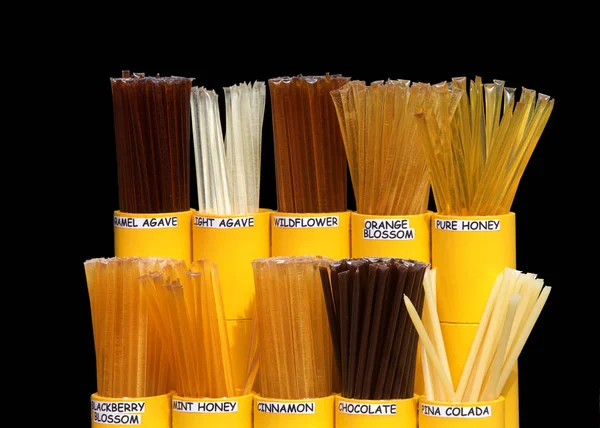Honey Straws of various flavors in a yellow display isolated on dark background. Honey is a healthy alternative to sugary snacks and candy.